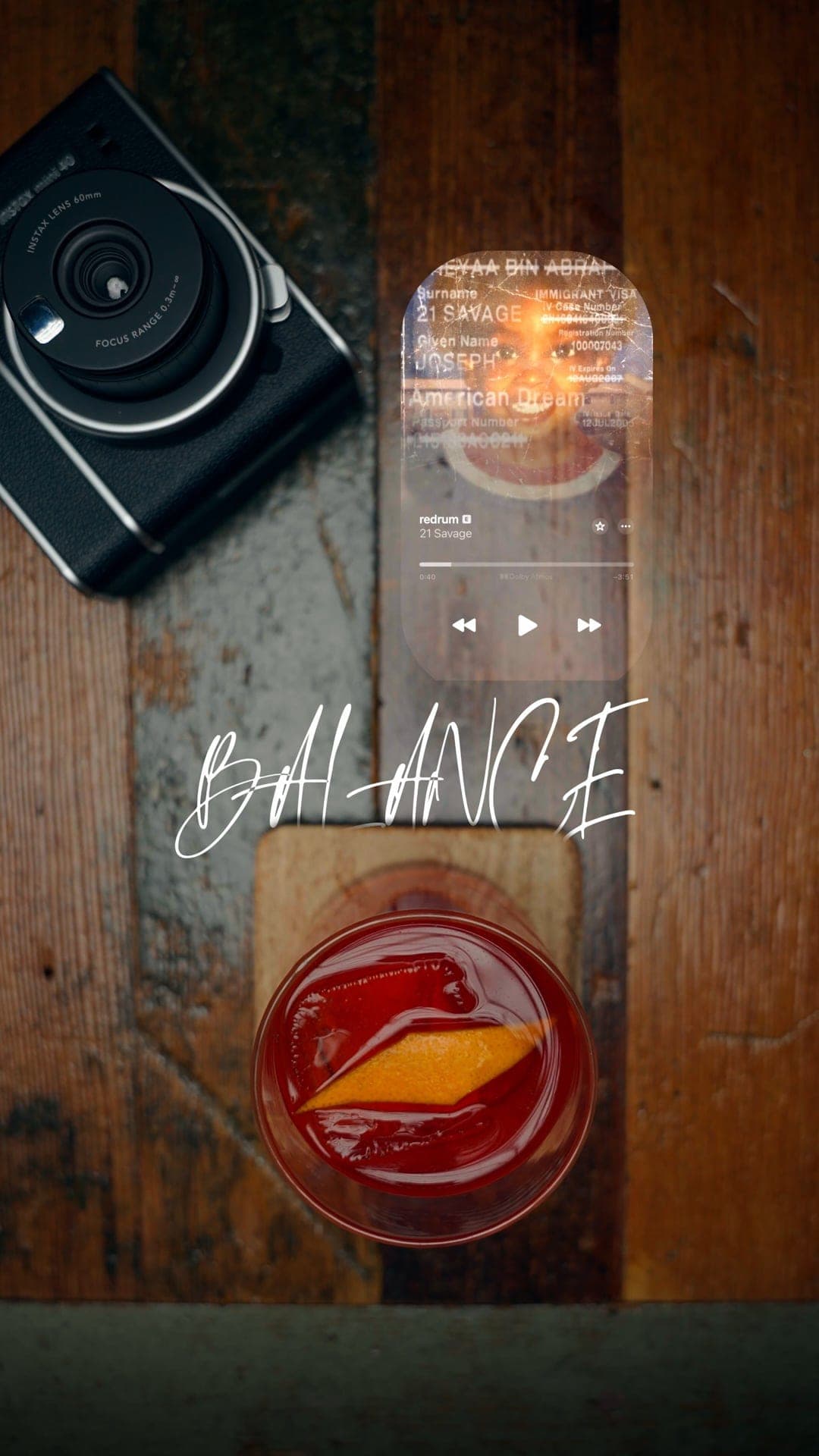 Reel still — a negroni with an orange peel beside a camera and a music-player overlay.